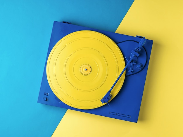 Vitrola de vinil amarelo e azul elegante em um fundo amarelo e azul. equipamento de música retro.