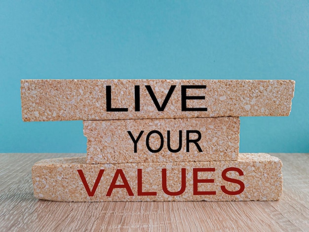Viva seu símbolo de valores Palavras do conceito Viva seus valores em blocos de tijolos Linda mesa de madeira