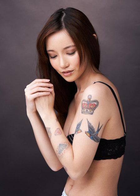 Vivemos com as cicatrizes que escolhemos foto de uma linda mulher tatuada posando em um estúdio