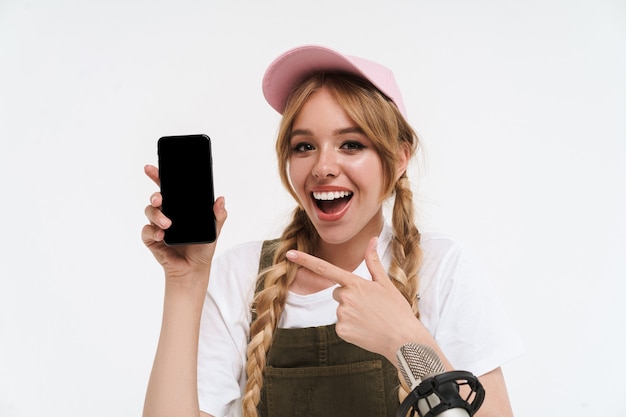 Vlogger alegre jovem loira fazendo um vídeo com diferentes dispositivos isolados no branco, mostrando a tela do celular em branco