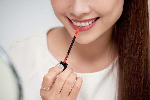 Vlogger de belleza profesional joven hermosa o blogger aplicando crema de lápiz labial en la boca, haciendo un tutorial de maquillaje