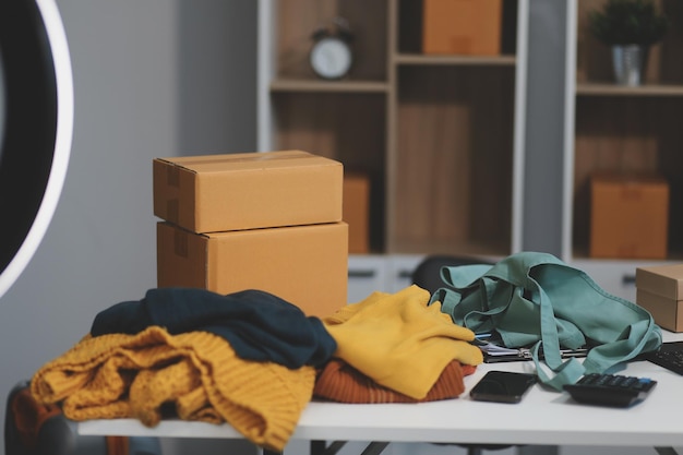 vlogger blogger pequeña PYME negocio mujer hermosa asiática usando teléfono móvil llamada de video para vender ropa transmisión en vivo venta en línea espectáculo producto presente detalle en la oficina de casa empresario comercio electrónico
