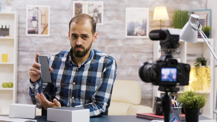 Foto vlogger famoso filmando el desempaquetado de un teléfono. influenciador creativo.
