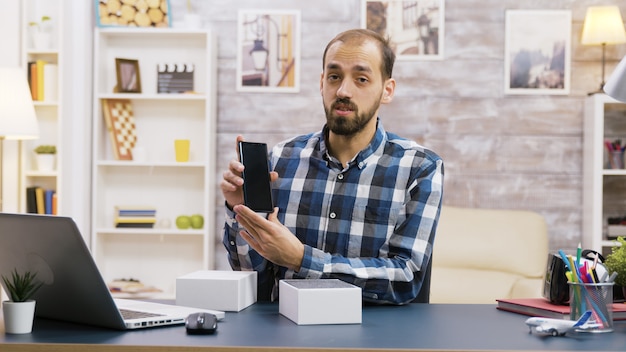 Vlogger masculino grabando el desempaquetado del nuevo teléfono. Creador de contenido famoso.