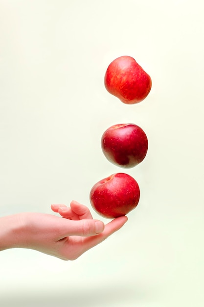 Voando levitando maçãs vermelhas frescas e suculentas no ar acima da mão feminina Levity frutas comida