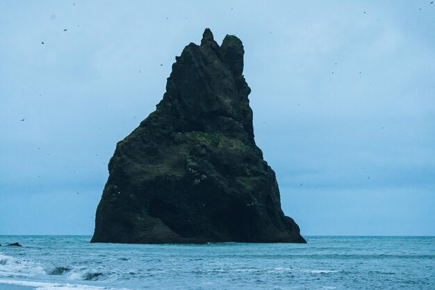 Foto voando sobre uma rocha solitária no mar da islândia