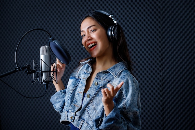 Vocalista con auriculares grabando una canción frente al micrófono en un profesional