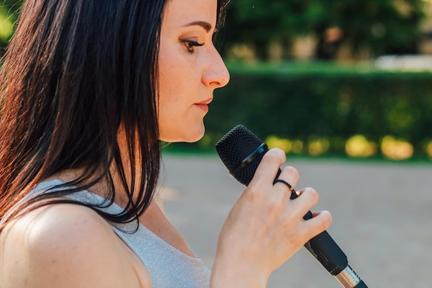 Vocalista femenina con cabello oscuro y vestido sostiene un micrófono en sus manos