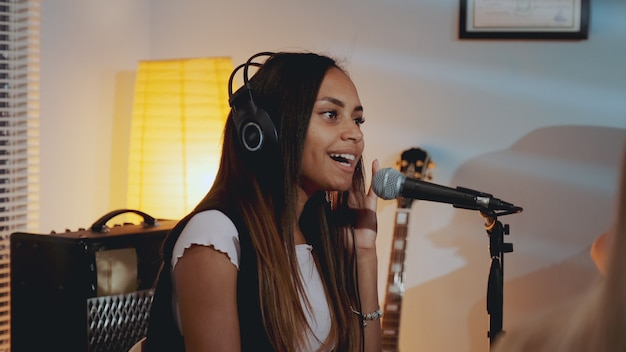 Vocalista feminina negra no fone de ouvido gravando sua nova música no estúdio em casa