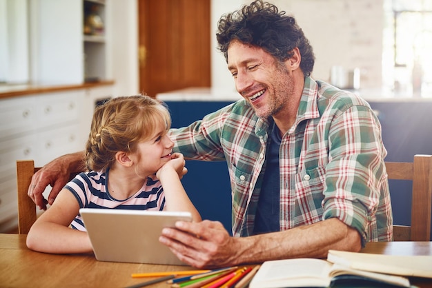Você é muito bom em explicar as coisas, ei, pai Foto recortada de um pai ajudando sua filha a completar a lição de casa em um tablet digital