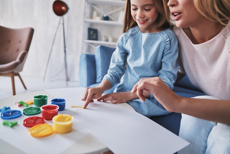Foto você está indo tão bem! mãe e filha pintando com os dedos e sorrindo enquanto passam o tempo em casa