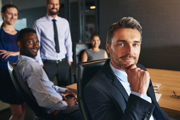 Foto você pode contar com minha equipe retrato de um empresário sentado em um escritório com colegas ao fundo