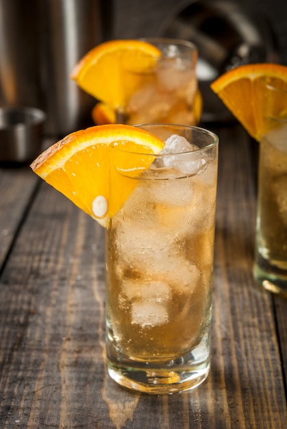 Vodka alcohólico Whisky Orange Highball Cocktail con una guarnición de naranja, en la mesa de madera copyspace