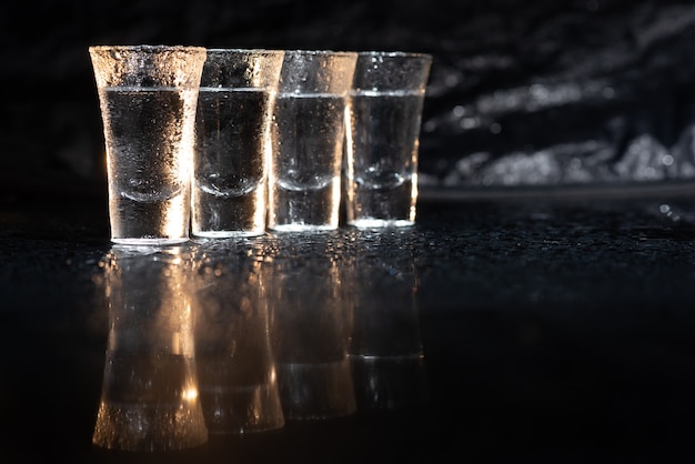 Vodka. Chupitos, vasos con vodka con hielo. Fondo oscuro. Copie el espacio Enfoque selectivo