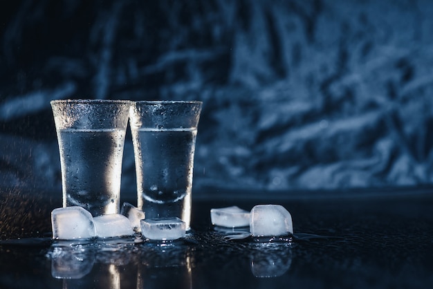 Vodka em copos de shot em fundo escuro.