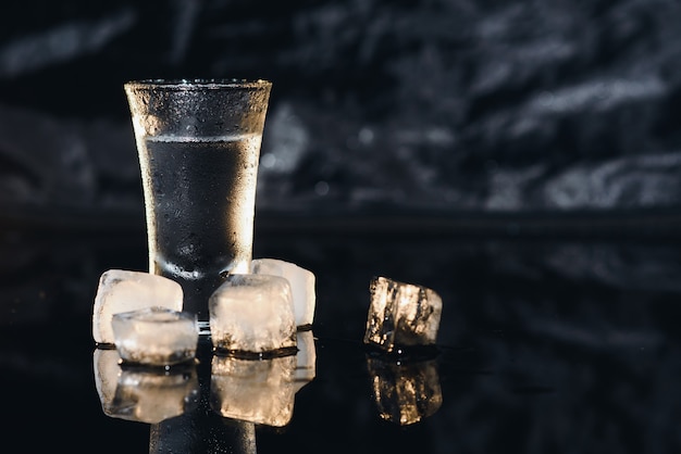 Vodka. Fotos, copos com vodka com gelo. Fundo escuro. Copie o espaço. Foco seletivo