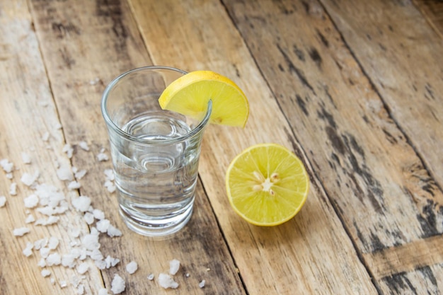 Vodka con limón sobre fondo de madera