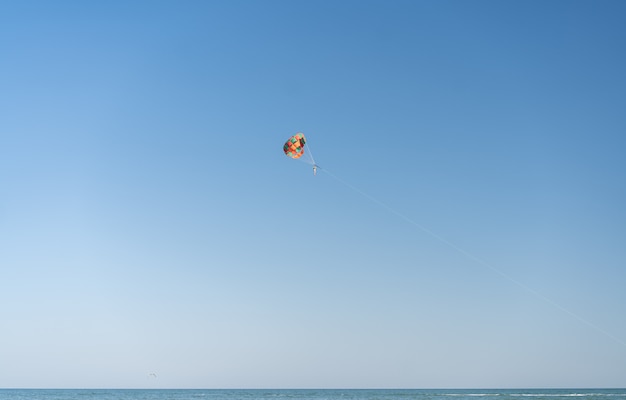 Voe com para-quedas colorido na praia