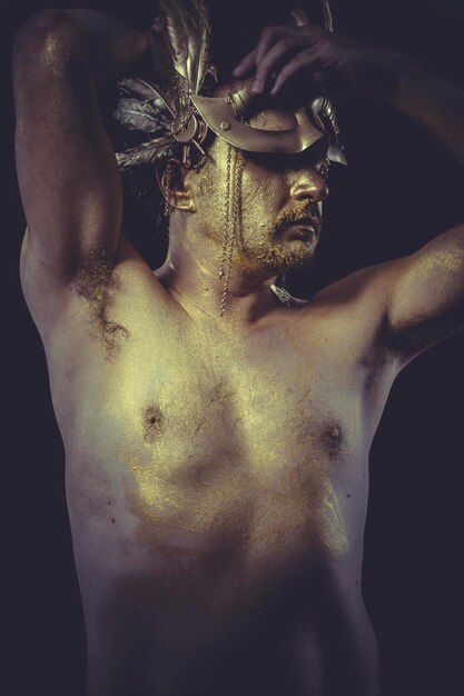 Vogue Man con cuerpo pintado máscara de plumas doradas y espada de acero