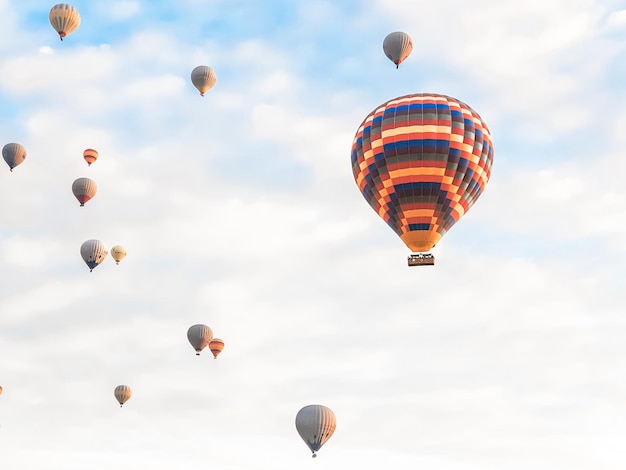 Foto volando en el cielo muchos bellos globos de colores brillantes en el aire en capadocia en las montañas temprano al amanecer llenando el globo con aire caliente del quemador gran canasta turistas excursión vuelo en la nube