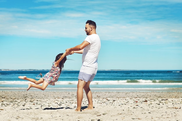 Volando con su padre Toma completa de un joven padre y su hija disfrutando de un día en la playa