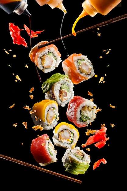 Foto volando trozos de sushi con palillos de madera y salsa