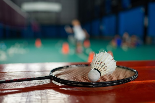 Volante de bádminton y raqueta con fondo de jugador borrosoxA