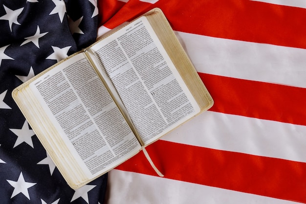 Volante de la bandera americana con abierto está leyendo el libro de la Biblia con oración por América sobre la bandera de los Estados Unidos