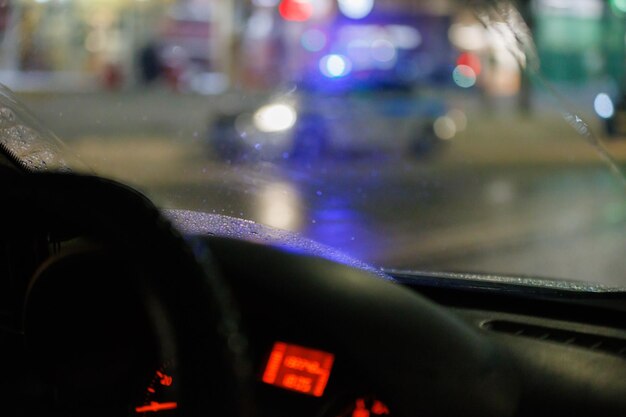 Volante borroso y salpicadero de coche con fondo de calle nocturno borroso