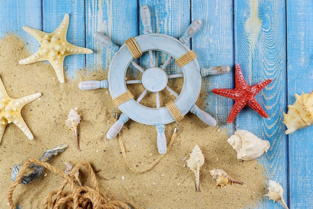 Volante decorativo con conchas de estrella de mar en la playa de arena con fondo de madera azul viejo