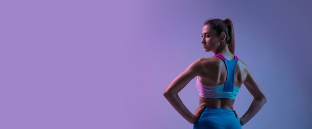 Volantes. Entrenamiento deportivo joven aislado sobre fondo de estudio degradado en luz de neón. Atlético y elegante. Deporte moderno, acción, movimiento, concepto de juventud. Hermosa mujer caucásica practicando.