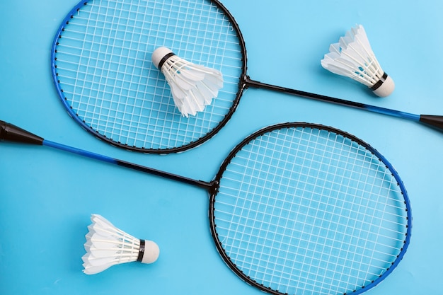 Foto volantes y raquetas de bádminton sobre fondo azul. vista superior