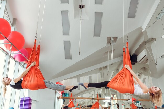 Volar yoga. dos mujeres practican yoga antigravedad con hamaca.