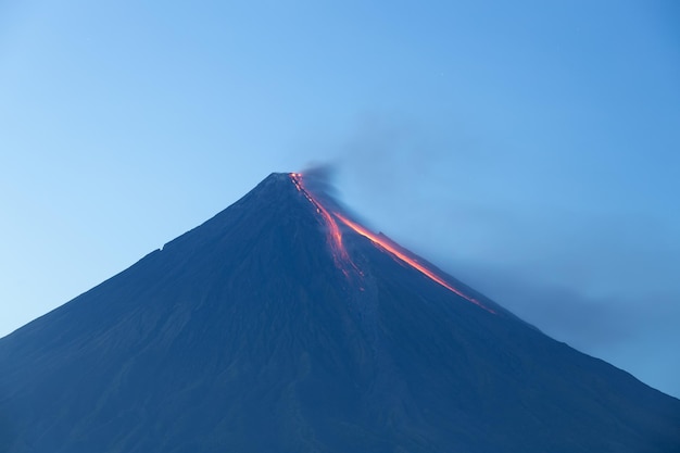 Volcán en erupción al atardecer arrojando lava