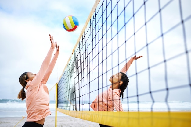 Voleibol de playa y ejercicio con deportistas jugando al aire libre para entrenar o competir Deporte de equipo y amigas en la arena junto a la costa para clavar una pelota durante un partido competitivo