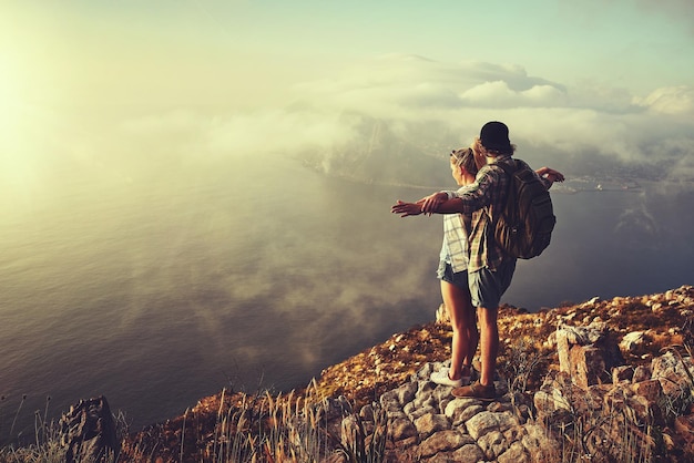 Volemos juntos Foto de una joven pareja aventurera admirando la vista desde el pico de una montaña mientras hacía una caminata