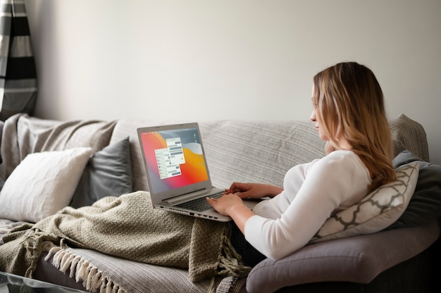 Foto voll erschossene frau, die mit laptop auf der couch arbeitet