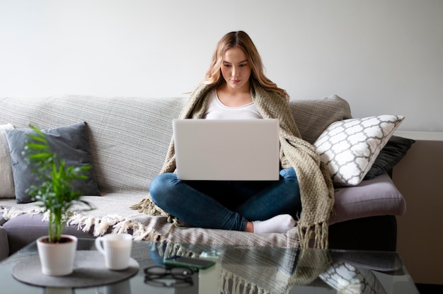 Foto voll erschossene frau, die zu hause mit laptop arbeitet