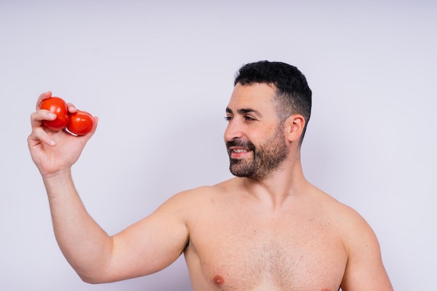 Voll isoliertes Studiobild von einem jungen nackten Mann mit Unterwäsche und Tomate