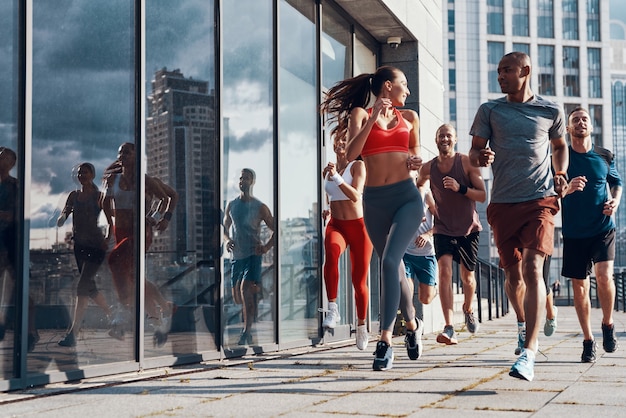 Foto volle länge von menschen in sportkleidung beim joggen auf dem bürgersteig im freien