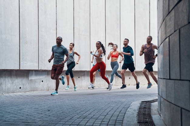 Volle Länge von Menschen in Sportkleidung, die beim Training im Freien joggen