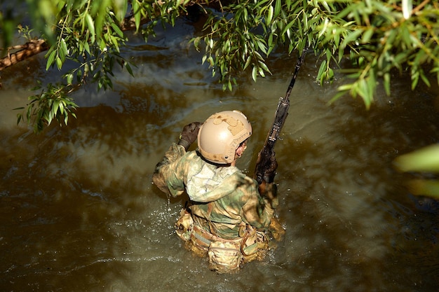 Volle militärische Erfahrung Ein Tageskommando, das mit einer automatischen Gewehrreplik durch das Wasser läuft