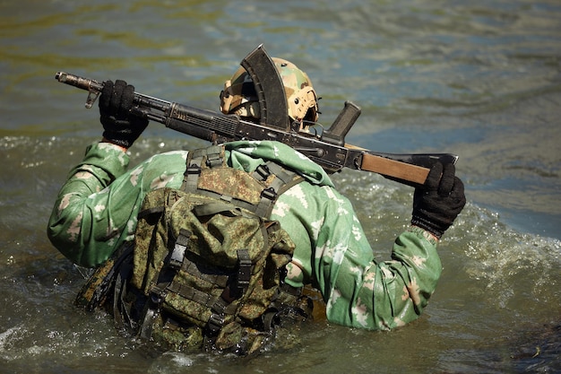 Volle militärische Erfahrung Ein Tageskommando, das mit einer automatischen Gewehrreplik durch das Wasser läuft