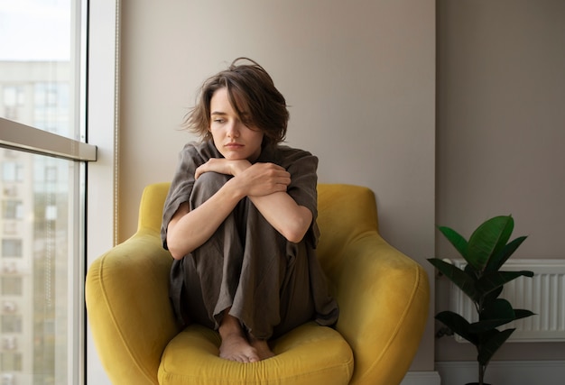 Volle Schussfrau mit der Angst, die auf Stuhl sitzt