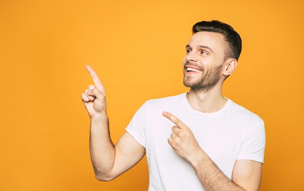 Voller angenehmer Emotionen zeigt der Junge im weißen Basic-T-Shirt auf etwas, was ihm wirklich Spaß macht und empfiehlt