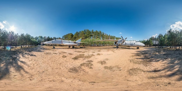 Volles sphärisches HDRI-Panorama 360-Grad-Winkelansicht im Waldguerillalager mit alten Militärtransportflugzeugen und Kampfflugzeug im Pinienwald in equirectangulärer Projektion VR-AR-Inhalt