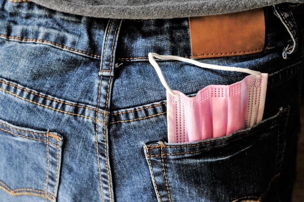 Foto vollformat-schuss rosa gesichtsmaske in der tasche einer blauen jeans-hose