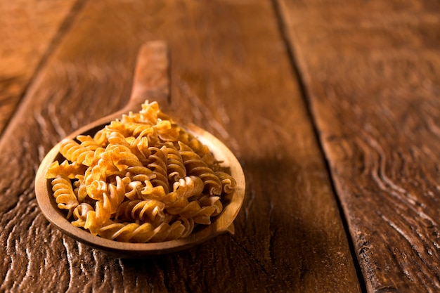 Vollkorn-Fusilli in einem Löffel. Integrale Pasta über einem Holztisch