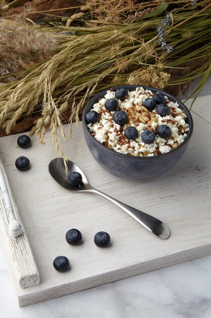 Vollkorn-Haferflocken mit Leinsamen und Blaubeeren auf weißem Jahrgang, serviert mit trockenem Kräuterbouquet