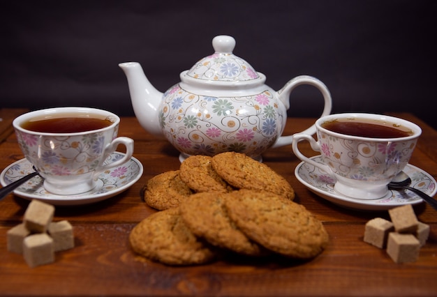 Vollkorn-Haferkekse mit einer Tasse Tee und Zucker auf einem Holztisch.